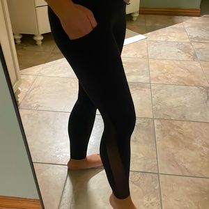 Black Athleta leggings with mesh accents and side pockets.